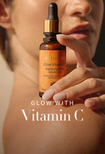 Hand holding a bottle of vitamin C serum with text 'Glow with Vitamin C' on a blurred background