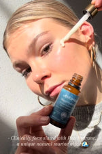 Person applying a dropper of skincare product to their face with Antipodes bottle in hand.