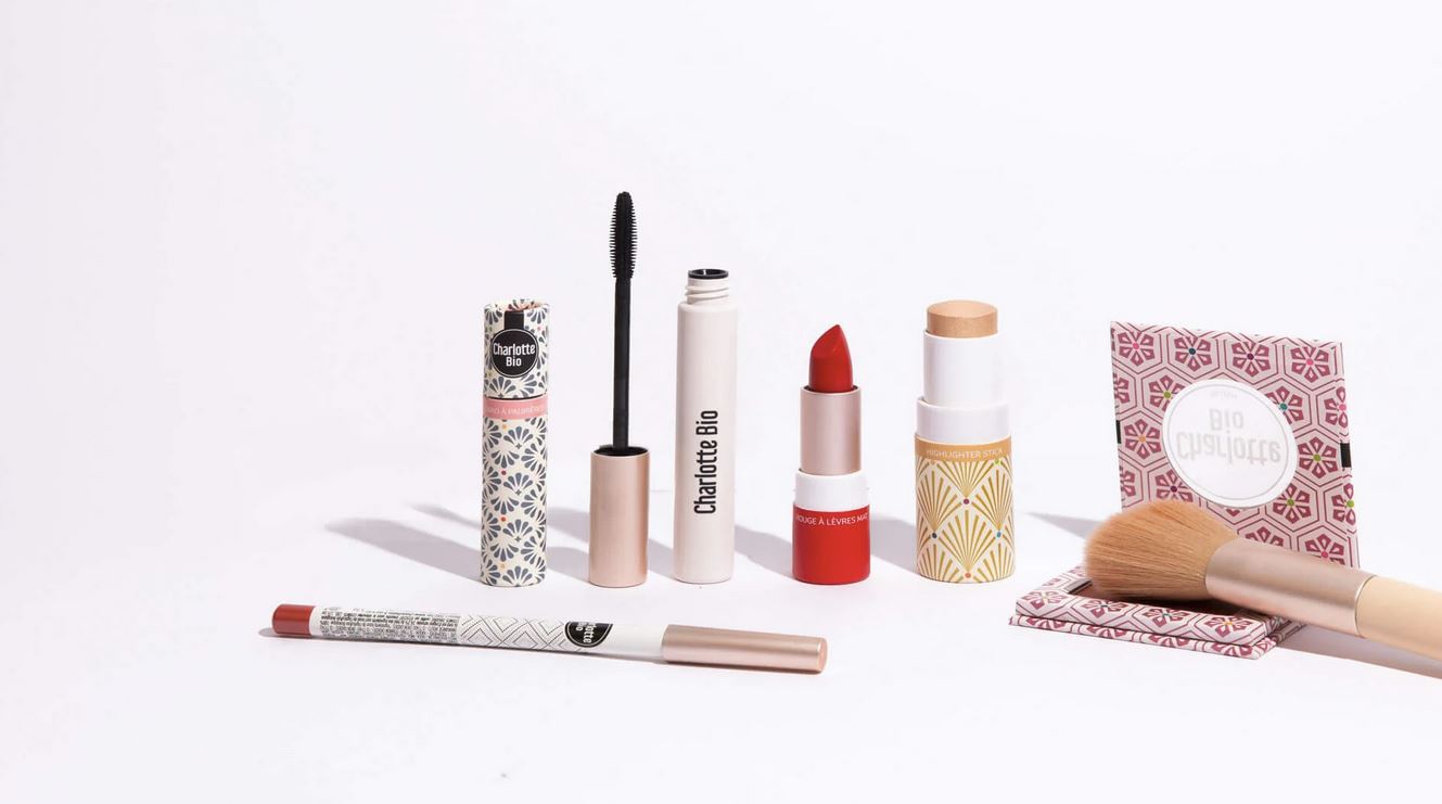 Collection of makeup products including lipsticks and brushes on a white background