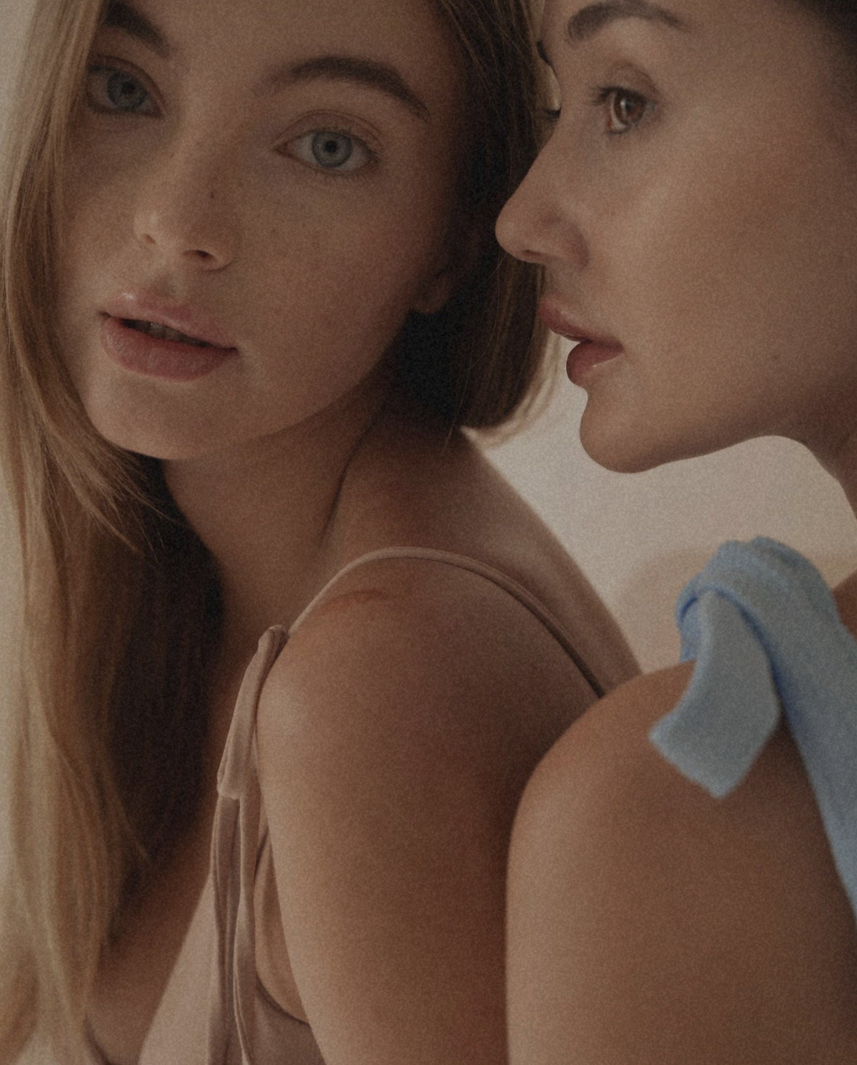 Two women standing close to each other with one holding a blue towel.