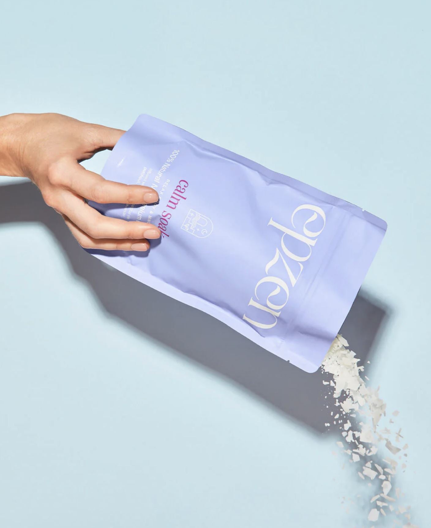 Hand holding a purple packet labeled Epzen with a light blue background